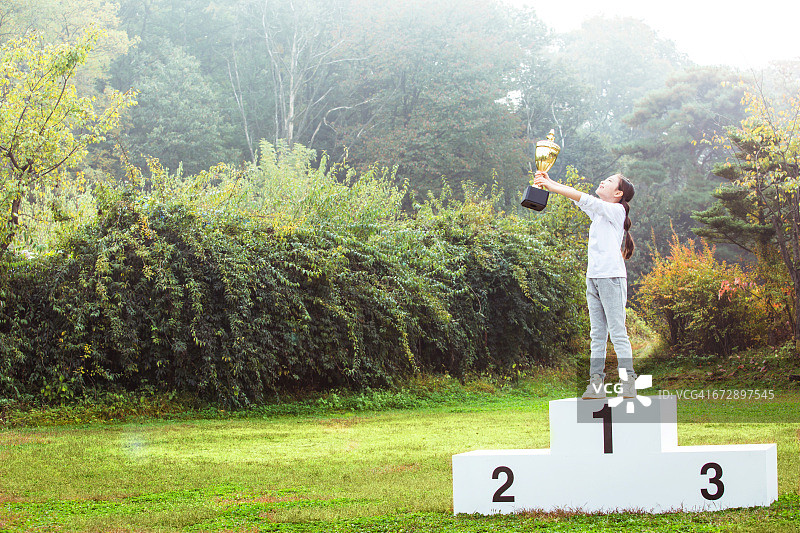 孩子们在领奖台上拿着奖杯图片素材