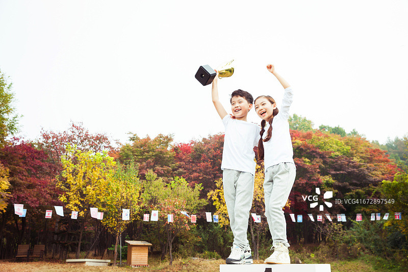 孩子们在领奖台上拿着奖杯图片素材