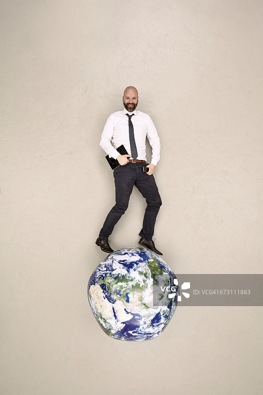 站在地球仪上手持移动设备的商人图片素材