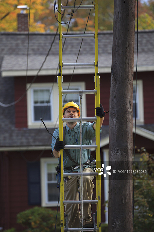 线路工攀爬电线杆上的梯子图片素材