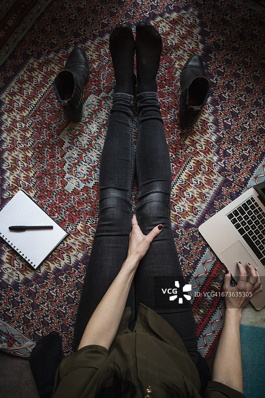 博主坐在地毯上使用笔记本电脑的下半身视角图片素材