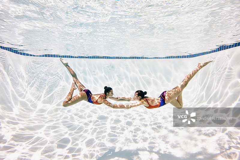 花样游泳运动员表演中手牵手图片素材