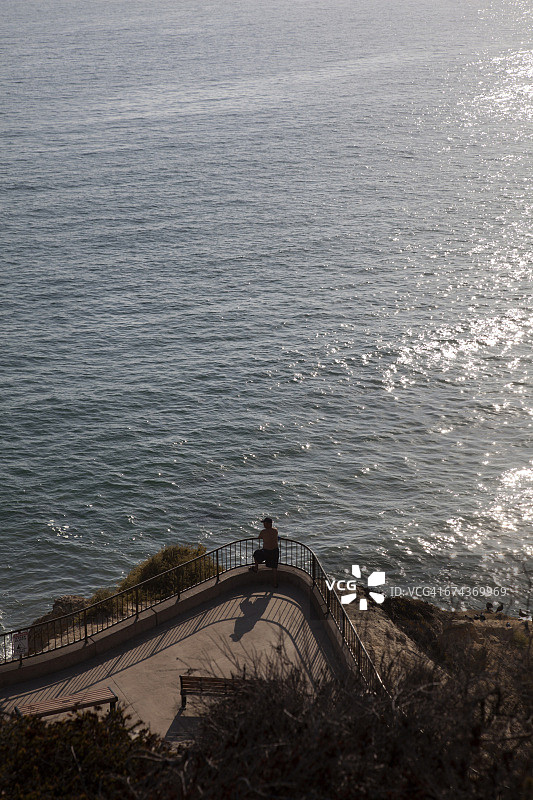 在悬崖边俯瞰大海的男人图片素材