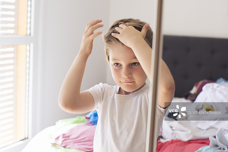 男孩在镜子前整理头发图片素材