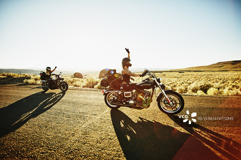 举起手臂骑在路上的摩托车手图片素材