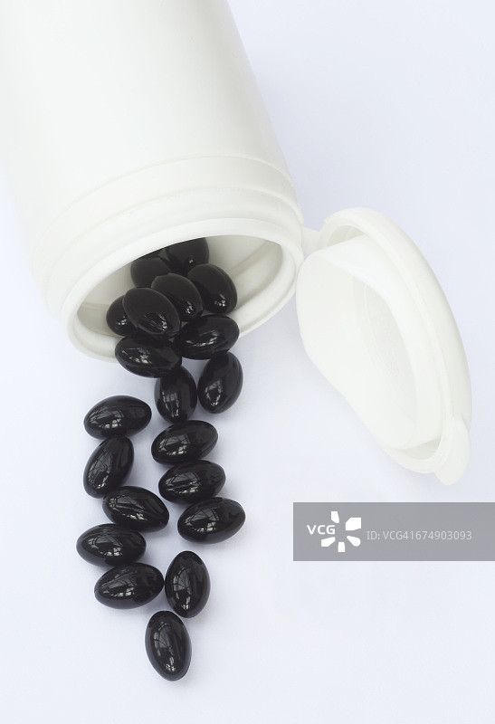 Q10黑色胶囊洒落白色表面图片素材