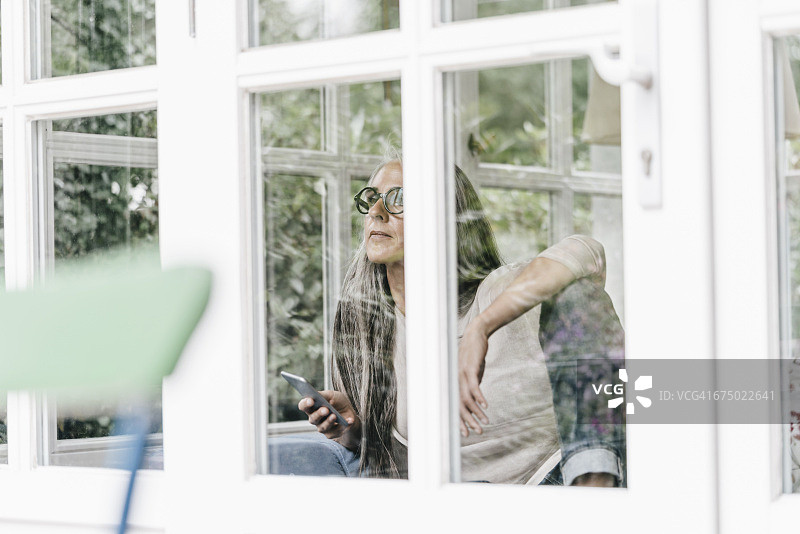 沉思的女人在冬季花园里望向窗外图片素材