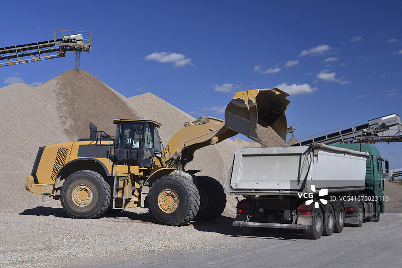 轮式装载机往卡车上装载砾石图片素材