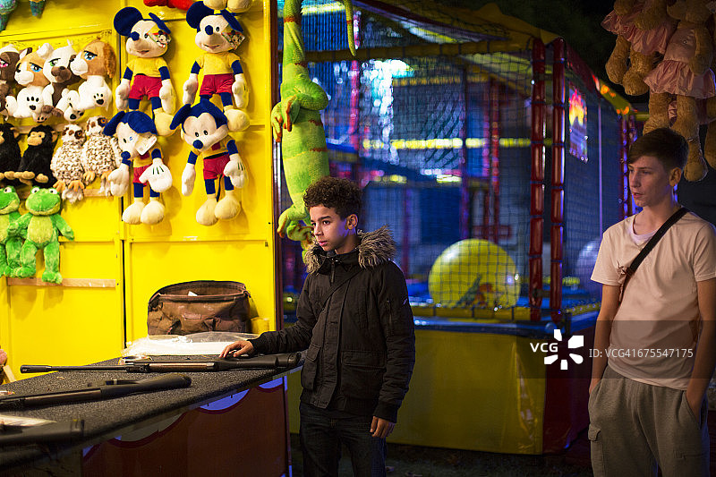夜晚游乐场摊位上的青少年男孩图片素材