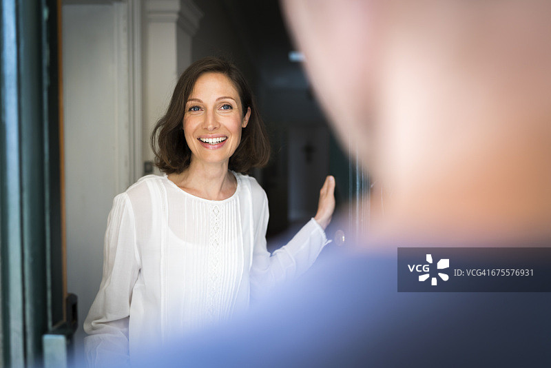面带微笑的中年妇女站在入口处图片素材