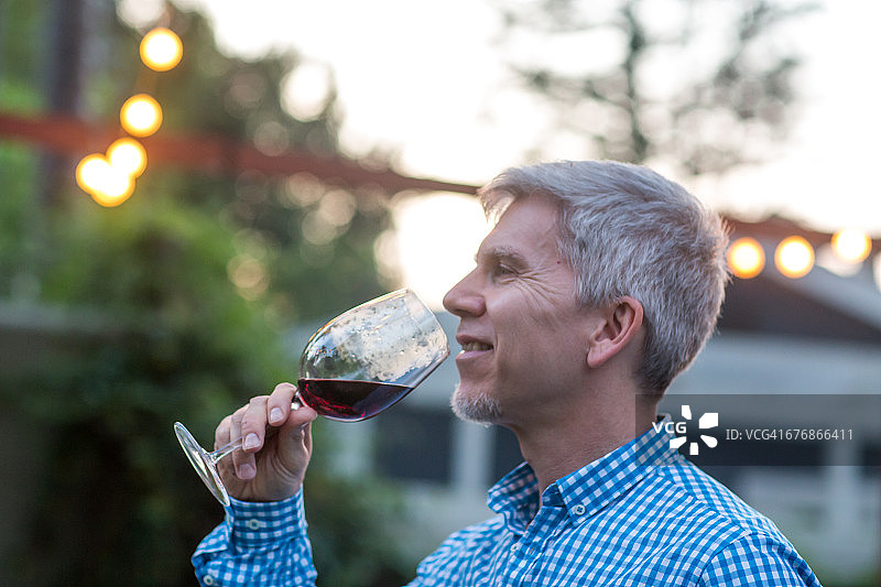 中年男人在花园派对黄昏时喝红酒图片素材