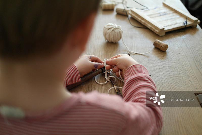 男孩在桌子上用木棍工作图片素材