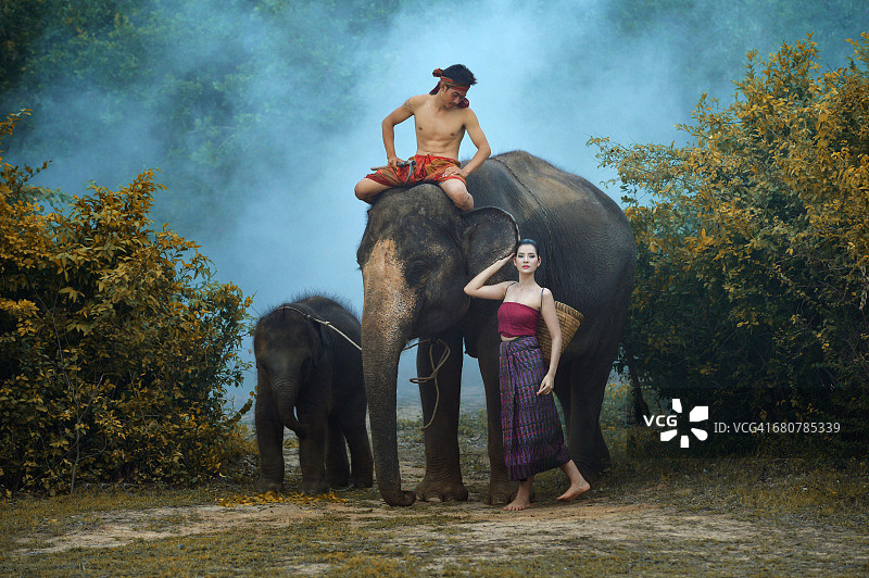 泰国驯象师骑大象旁站女人小象图片素材