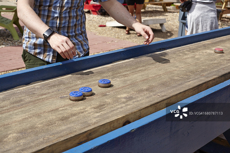 年轻男人玩桌面冰壶图片素材