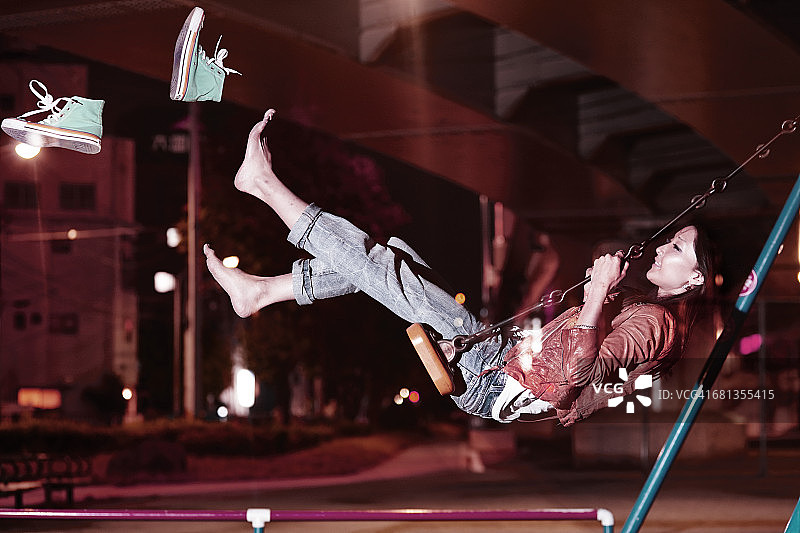 一个女人在秋千上甩掉了鞋子图片素材