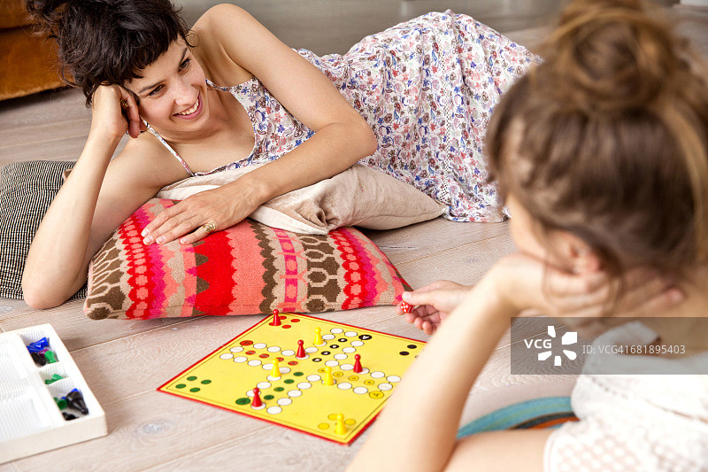 两个好朋友在家里的地板上玩飞行棋图片素材