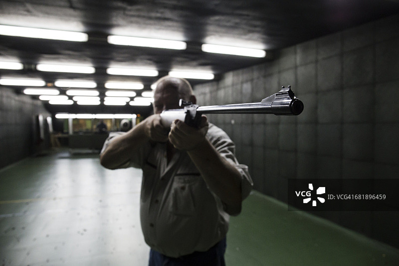 在室内射击场用卡宾枪瞄准的男人图片素材
