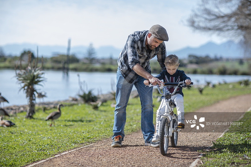 父亲扶着儿子骑自行车图片素材