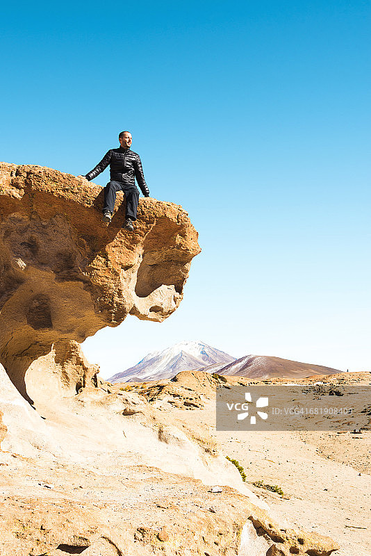 男人坐在岩石顶上图片素材