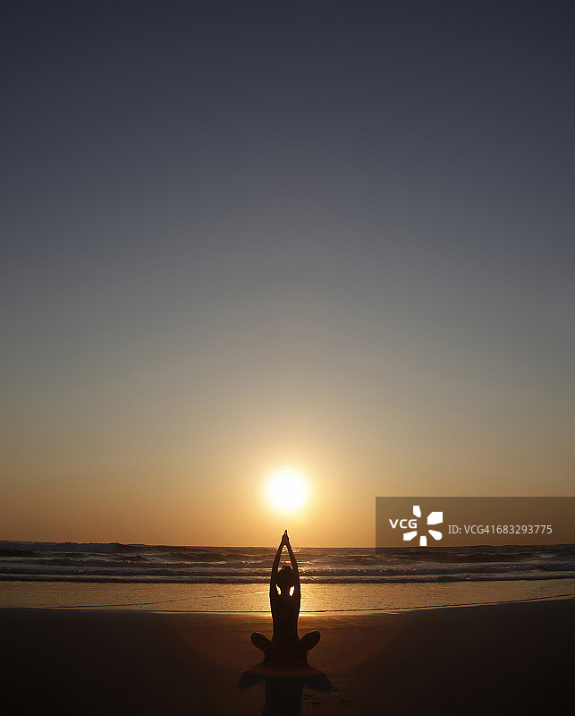 日落时在海滩上做瑜伽的女人图片素材