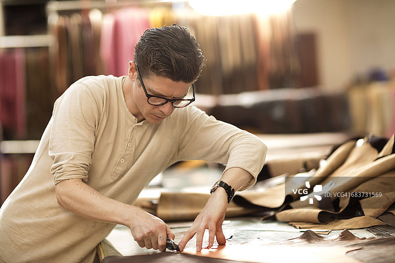 男人在皮革厂用美工刀切割皮革图片素材