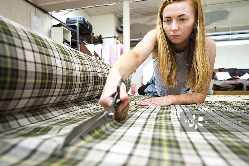在皮夹克制造厂切割布料的年轻女人图片素材