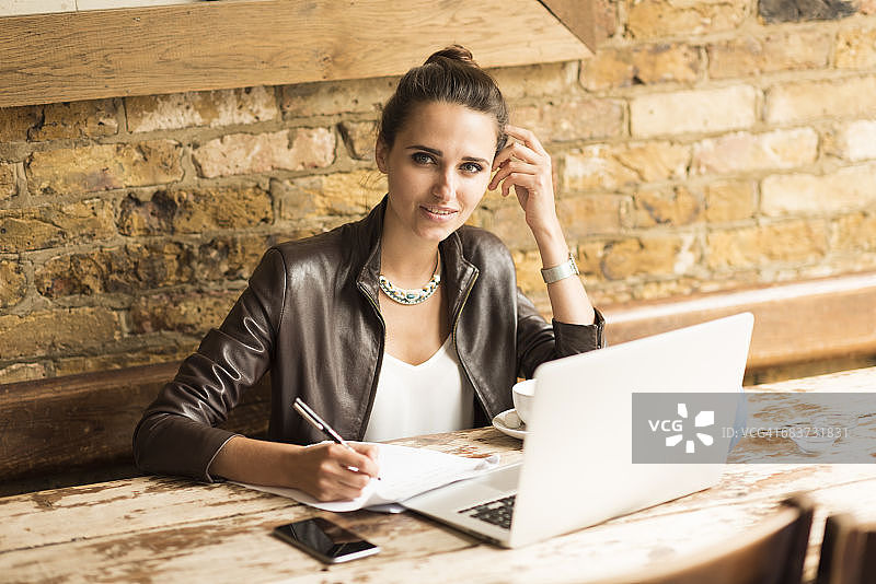 年轻女商人在咖啡馆做笔记的肖像图片素材