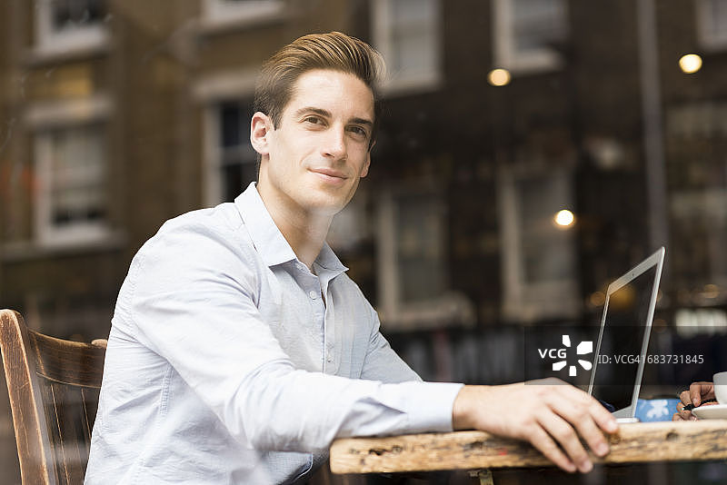 咖啡馆里用笔记本电脑的年轻商人窗外景色图片素材
