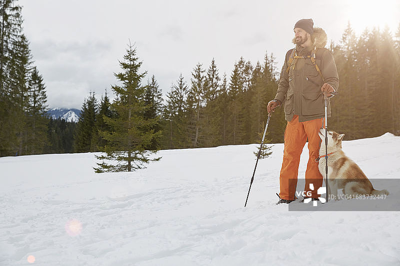 中年男人在德国巴伐利亚州埃尔毛穿着雪鞋，狗在他旁边图片素材