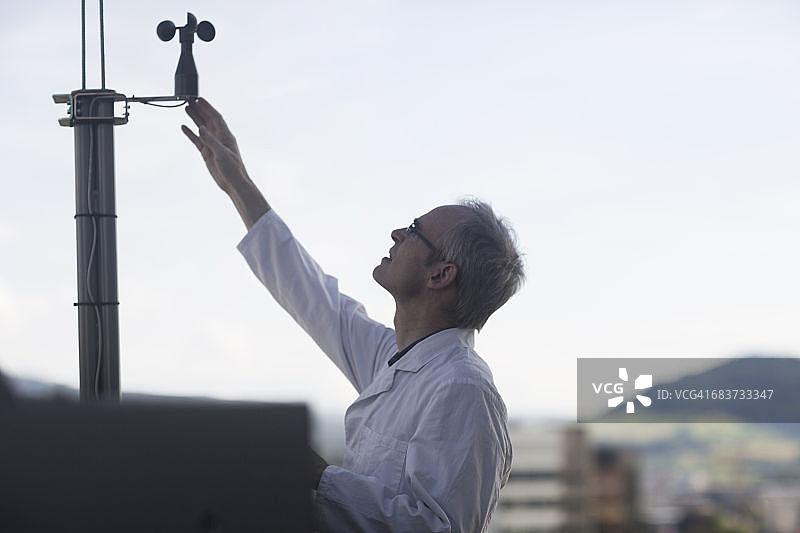 在气象站使用风速计测量风力的男气象学家图片素材