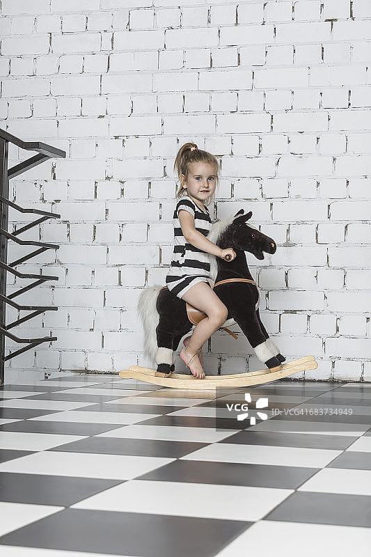 女孩在家中靠墙玩摇摇马肖像图片素材