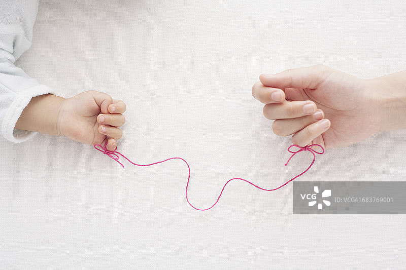 母亲和婴儿用红线系着小指图片素材