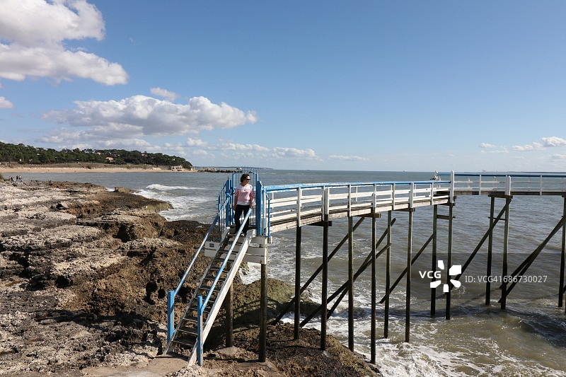 在法国滨海圣帕莱，站在木制码头台阶上的女人图片素材