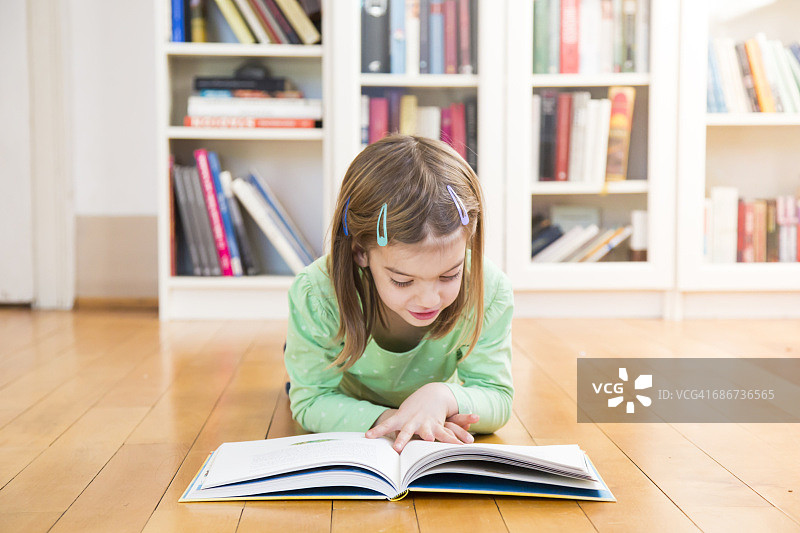躺在地板上看书的小女孩图片素材