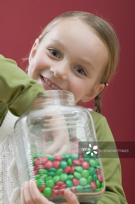 从糖罐里吃巧克力豆的小女孩图片素材