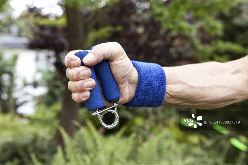 年长的男人在花园里用握力器进行健身训练图片素材