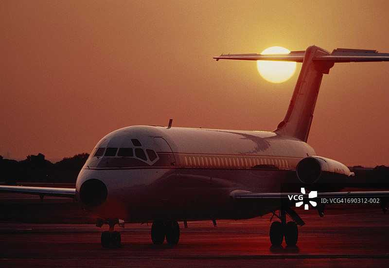 日落时分停机坪上的麦克唐纳·道格拉斯MD-80客机图片素材