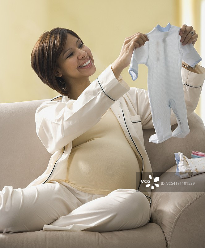 孕妇看着婴儿的衣服图片素材