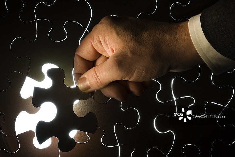 人物拼上最后一块拼图的手部特写图片素材