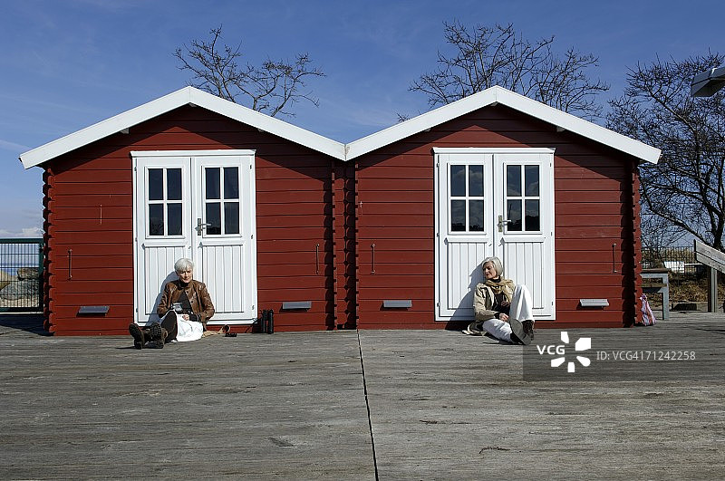 两名中年妇女坐在小屋前图片素材