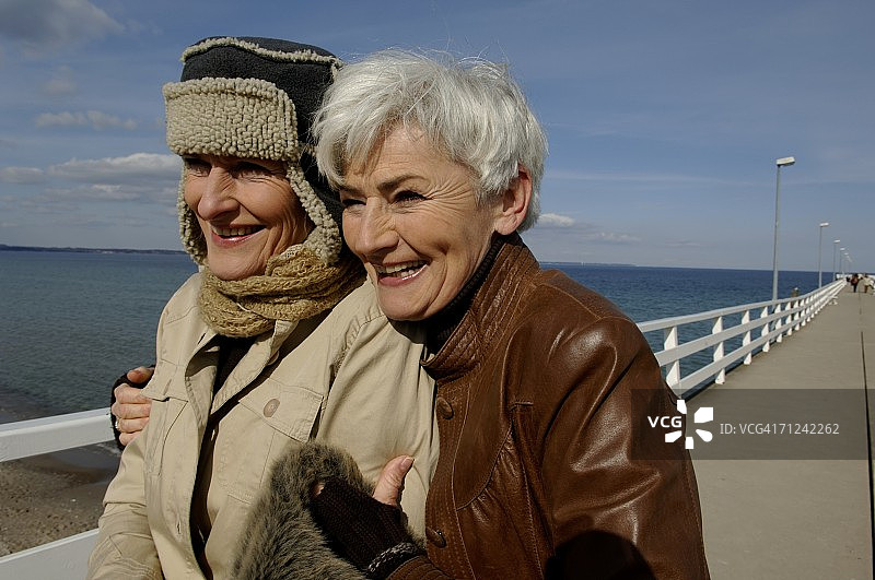 在波罗的海沿岸行走的两个欢笑的中年妇女图片素材