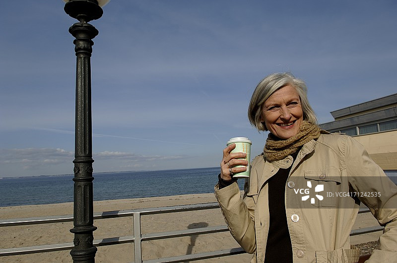 中年妇女在波罗的海海滩上手拿咖啡杯图片素材