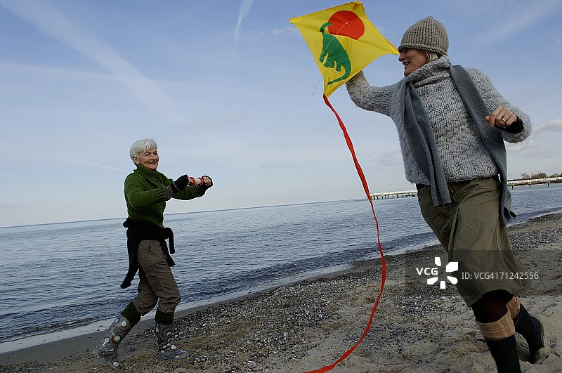 两位中年妇女在波罗的海海滩放风筝图片素材
