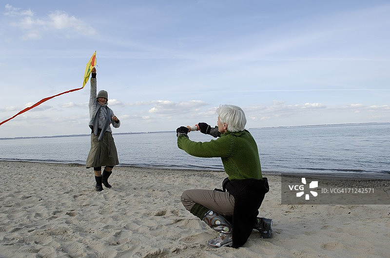 两位中年妇女在波罗的海海滩放风筝图片素材