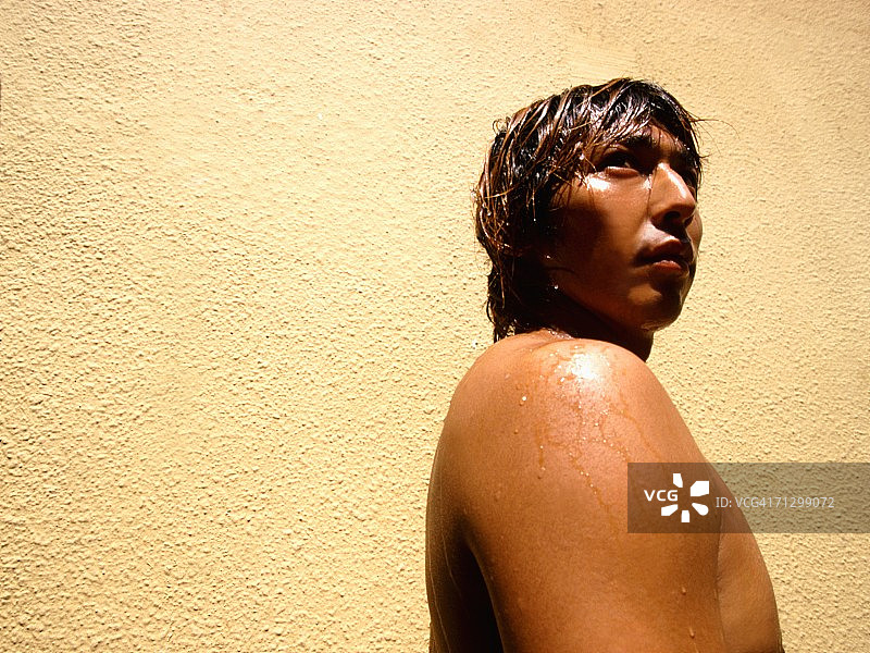 年轻男人靠墙站立的侧面照图片素材