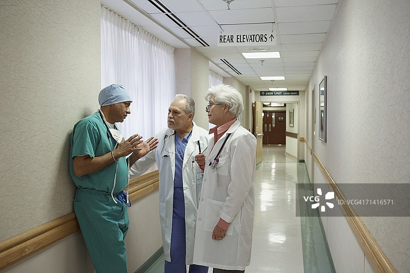 外科医生在医院走廊里和两位医生交谈图片素材