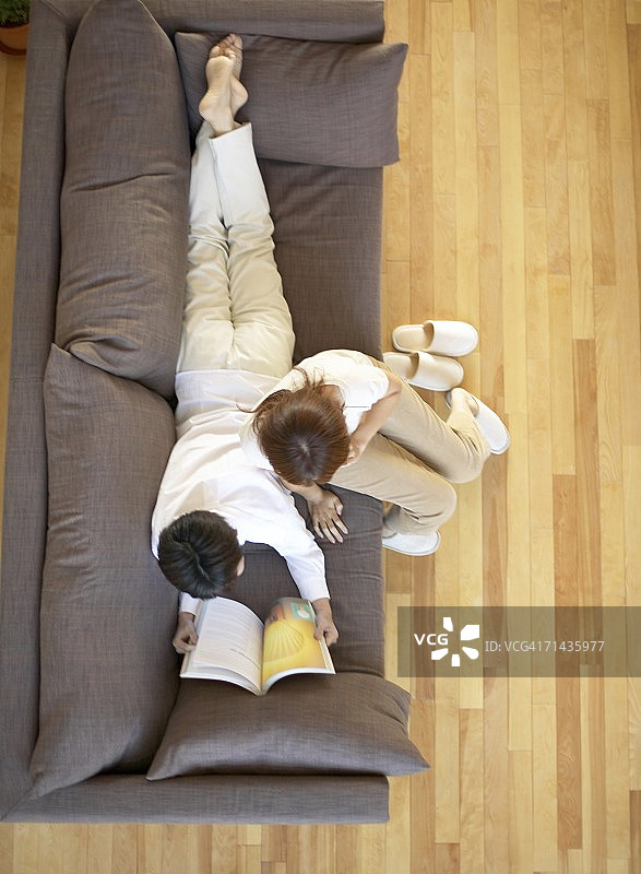 年轻情侣在沙发上读书图片素材