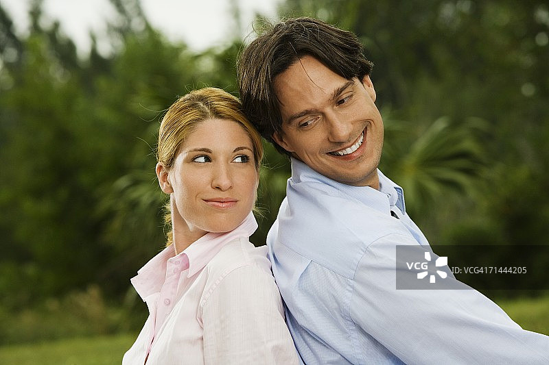 在公园里背靠背坐着的男商人和女商人侧面像图片素材