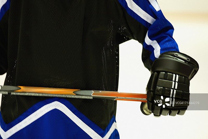冰球运动员拿着冰球杆的腰部视角图片素材