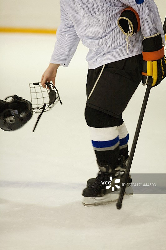 冰球运动员手持冰球鞋和头盔的侧面照图片素材